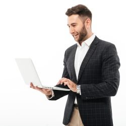 Portrait of a confident bearded man using laptop computer while standing isolated over white background